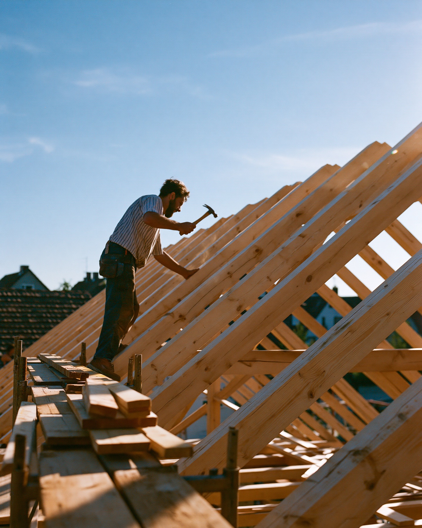 Dachdecker auf dem First einer Holzkonstruktion im Sommerlicht